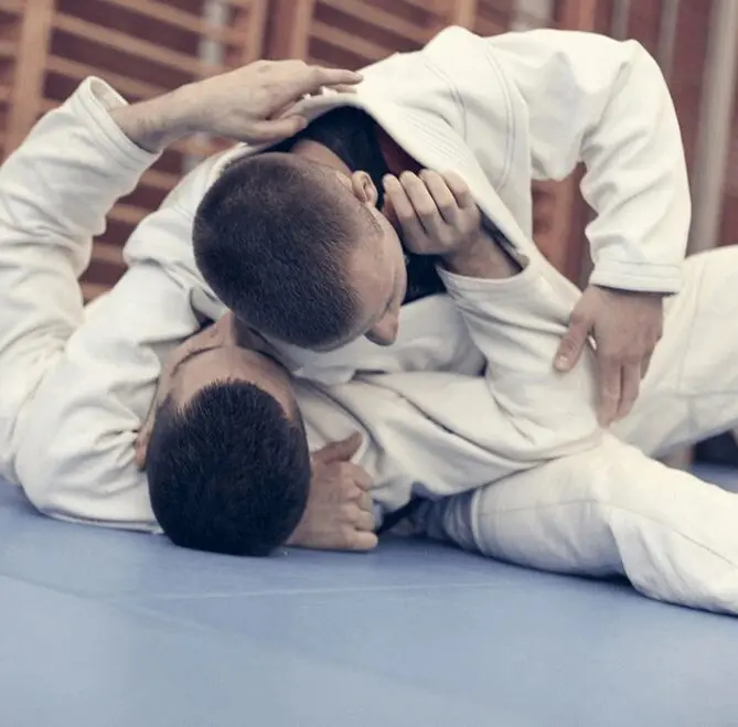 Two men are practicing judo on a blue mat.